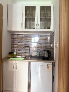 a kitchen with white cabinets and a sink and a refrigerator at Splendid corner in Bečići