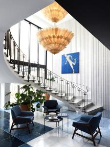 a lobby with a staircase and chairs and a chandelier at Grand Hotel Flora in Sorrento