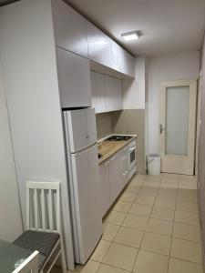 a kitchen with white cabinets and a white refrigerator at Apartman Ðurđevak in Stara Pazova