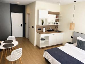 a bedroom with a bed and a table and a kitchen at Ahiva Village in Fulhadhoo