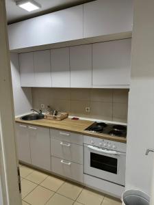 a kitchen with white cabinets and a stove and a sink at Apartman Ðurđevak in Stara Pazova