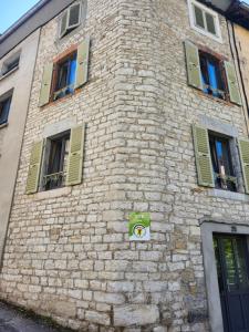 a brick building with green windows and a sign on it at La Tour Cicon in Salins-les-Bains