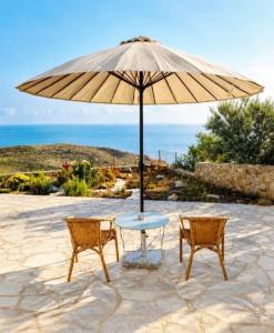 a table and two chairs under an umbrella at Ελαιόλιθοι Μάνη Villas in Oitylo