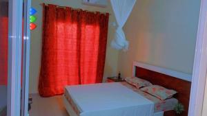 a bedroom with a bed with a red curtain at Keur Massar Tolou Laye WADE in Niadyorane