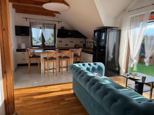 a living room with a blue couch and a kitchen at Noclegi AirportPark in Pyrzowice