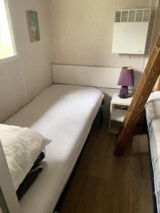 a small room with a bed and a night stand with a lamp at Camping montagne in Camurac