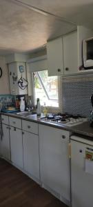 a kitchen with white cabinets and a stove top oven at Camping montagne in Camurac