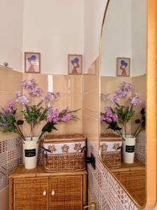 a bathroom with three vases of purple flowers on two dressers at B&B La Meta in Benevento