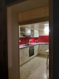 a kitchen with white cabinets and a red wall at Ferienwohnung Prignitzhof in Plattenburg