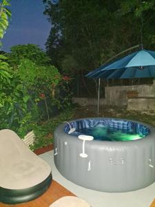 a hot tub with an umbrella and a chair at Gite de Germaine in Sainte-Anne