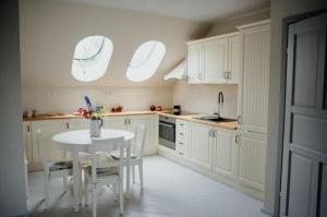 a kitchen with white cabinets and a white table and chairs at Flowland Tarczyn in Tarczyn