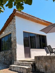 a white house with a chair and an umbrella at Perseku GuestHouse in Shirokë