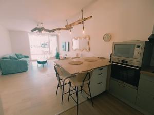 a kitchen with a table with chairs and a microwave at Les pieds dans l'eau in Mèze