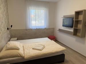 a bedroom with a bed and a tv on the wall at RoyalHill Apartman in Vonyarcvashegy