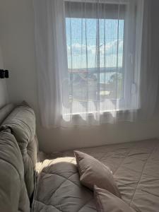 a bed with two pillows in front of a window at Nest apartman 2 in Veliko Gradište