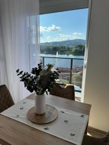 a vase of flowers on a table with a window at Nest apartman 2 in Veliko Gradište
