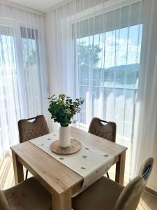 a dining room table with a vase of flowers on it at Nest apartman 2 in Veliko Gradište +8 photos