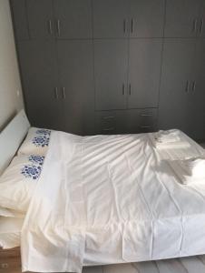 a bed with white sheets and cabinets in a bedroom at stavros house byzarkco in Porto Rafti