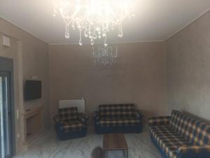 a living room with two couches and a chandelier at stavros house byzarkco in Porto Rafti
