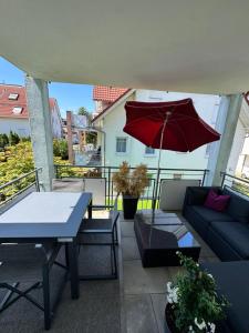 a patio with a couch and a red umbrella at Ferienwohnung Homburger - Immenstaad am Bodensee in Immenstaad am Bodensee