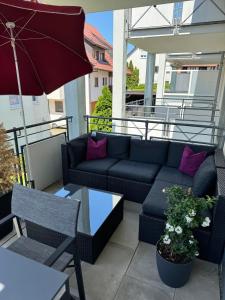 a patio with a couch and a table and an umbrella at Ferienwohnung Homburger - Immenstaad am Bodensee in Immenstaad am Bodensee