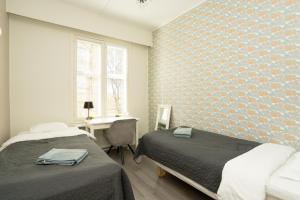 a bedroom with two beds and a desk with a window at Majatalo Mäntän Kuusela in Mänttä