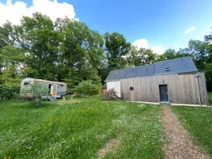 a barn and a trailer in a grass field at Roulotte in Huismes