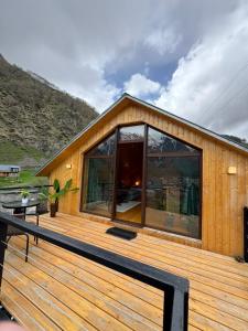 a house with a large deck with glass windows at Cabin AISI in (( Gergeti ))