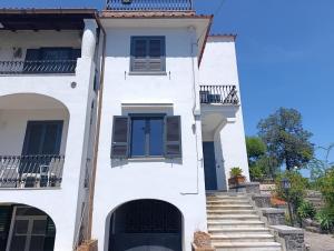 a white house with blue doors and stairs at Villa Rosa Rooms in Ischia Town