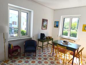 a living room with a table and chairs and windows at Villa Rosa Rooms in Ischia Town +16 photos