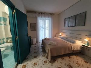 a bedroom with a bed and a bathroom with a toilet at Villa Rosa Rooms in Ischia Town