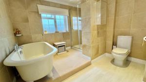 a bathroom with a white tub and a toilet at The Coach House in Braunton +10 photos