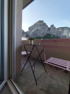 a balcony with a table and a view of a mountain at Meteora Gold and Glass in Kalabaka