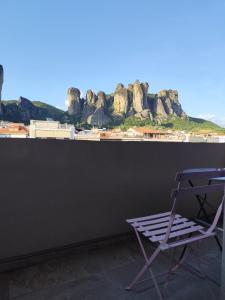 a chair sitting next to a wall with a view of rocks at Meteora Gold and Glass in Kalabaka