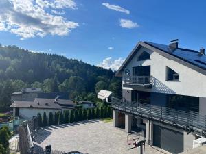 a white building with a balcony and a mountain at Breńskie Tarasy in Brenna