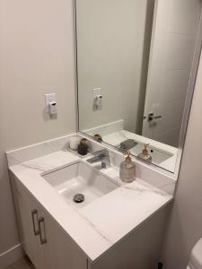 a white bathroom with a sink and a mirror at Cozy home in Burnaby