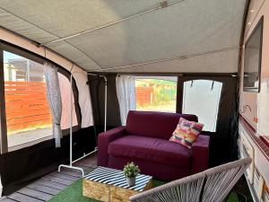a living room in a tent with a purple couch at Domki i przyczepy Kemping Sunday Camp in Władysławowo +29 photos