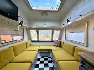 a living room with a yellow couch and a checkered floor at Domki i przyczepy Kemping Sunday Camp in Władysławowo