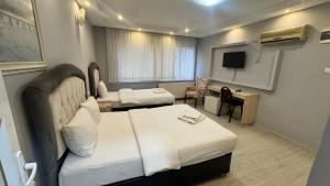 a hotel room with two beds and a desk at Pera City Otel in Samsun
