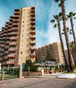 a tall building with palm trees in front of it at Atico estudio en 1°linea Almuñecar in Almuñécar