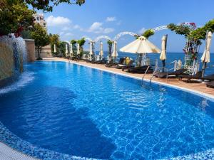 a pool with chairs and umbrellas next to the ocean at Luxurious and panoramic apartments at the beach in La Mer complex in Golden Sands