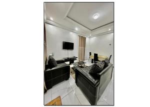 a living room with two black leather couches and a television at Résidence ADJOBIA - Grâce divine YAMOUSSOUKRO in Yamoussoukro