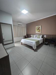 a bedroom with a bed and a table and a mirror at Hotel Mohallem in Passos