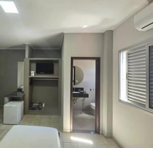 a bedroom with a bed and a window and a mirror at Hotel Mohallem in Passos
