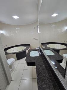 a bathroom with two sinks and two toilets at Hotel Mohallem in Passos