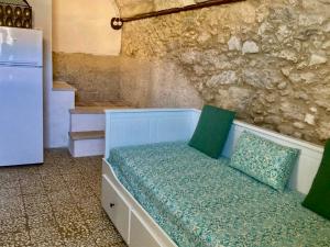 a room with a bed with green pillows and a refrigerator at Pedra e Lozzu in Sedini