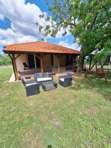 a pavilion with couches and a picnic table in a field at Apartmani Milojević in Boljevac