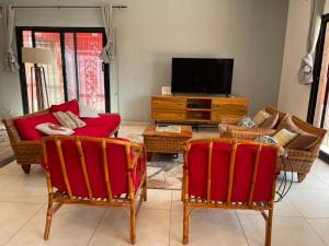 a living room with red chairs and a television at Paradise in Yène