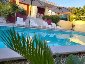 a pool with chairs and umbrellas next to a house at Villa Bona - Private Pool Oasis in Mostar