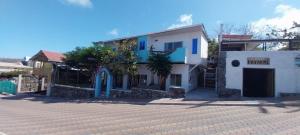 a white house with blue doors on a street at Hostal Cabañas Don Jorge in Puerto Baquerizo Moreno